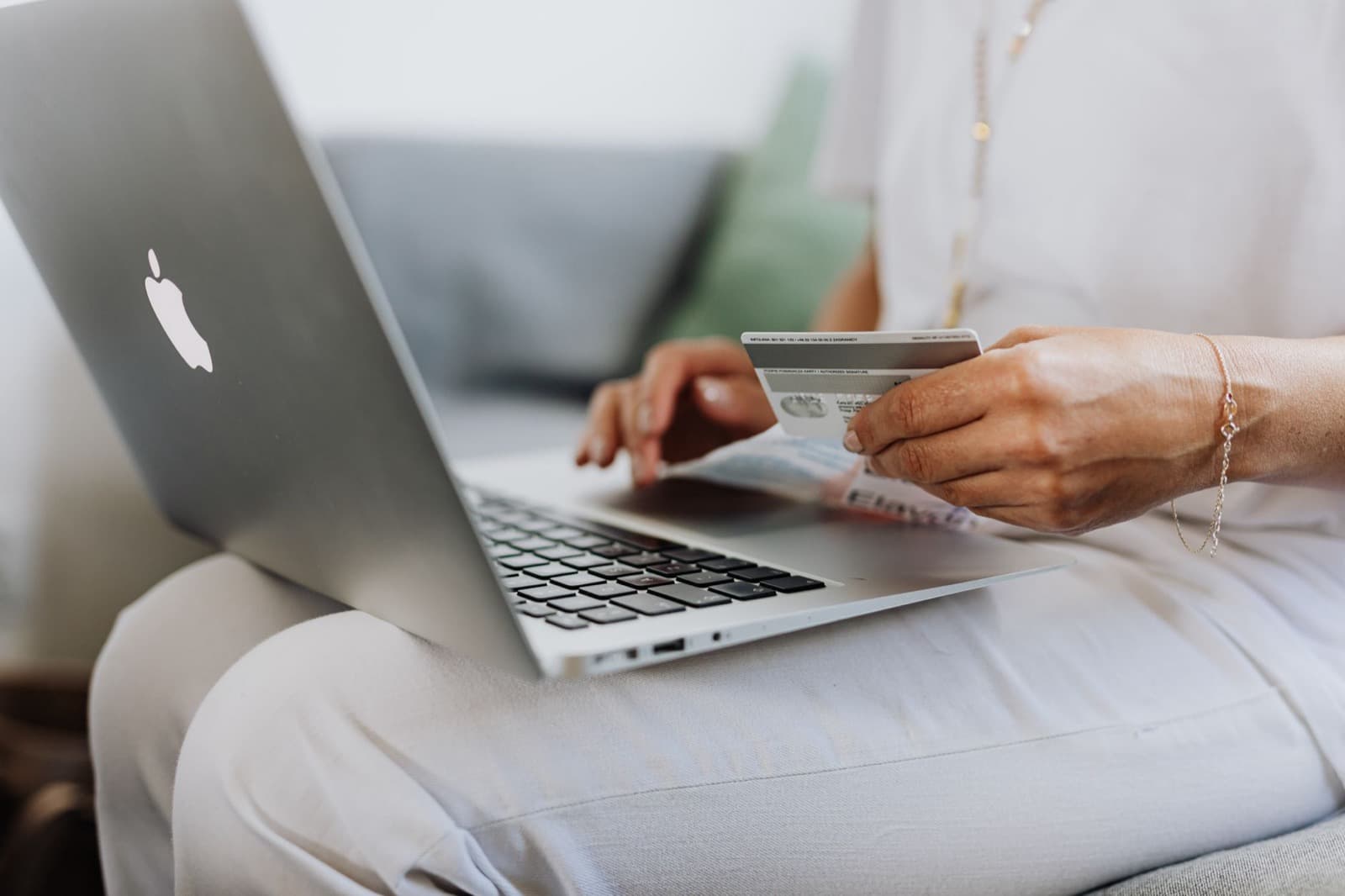 Someone shopping online at a laptop holding a bank card